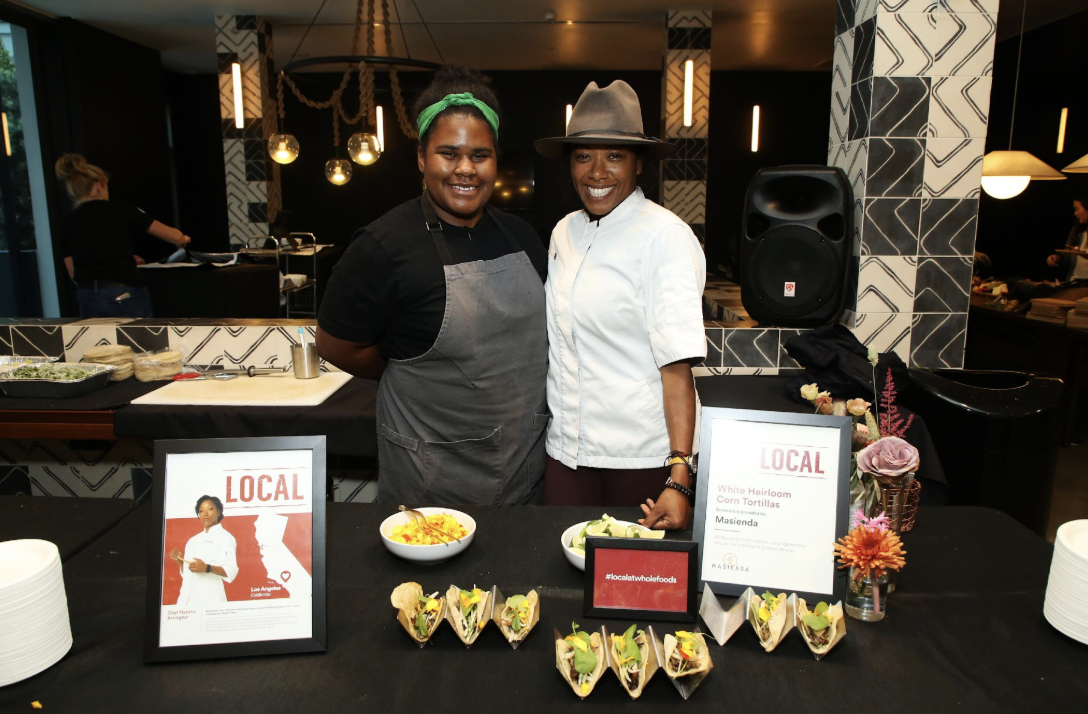 Two women presenting local food at a We Love Local event
