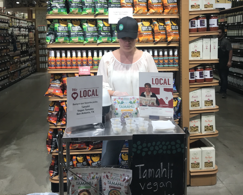Supplier presenting products at a demo table inside Whole Foods Market